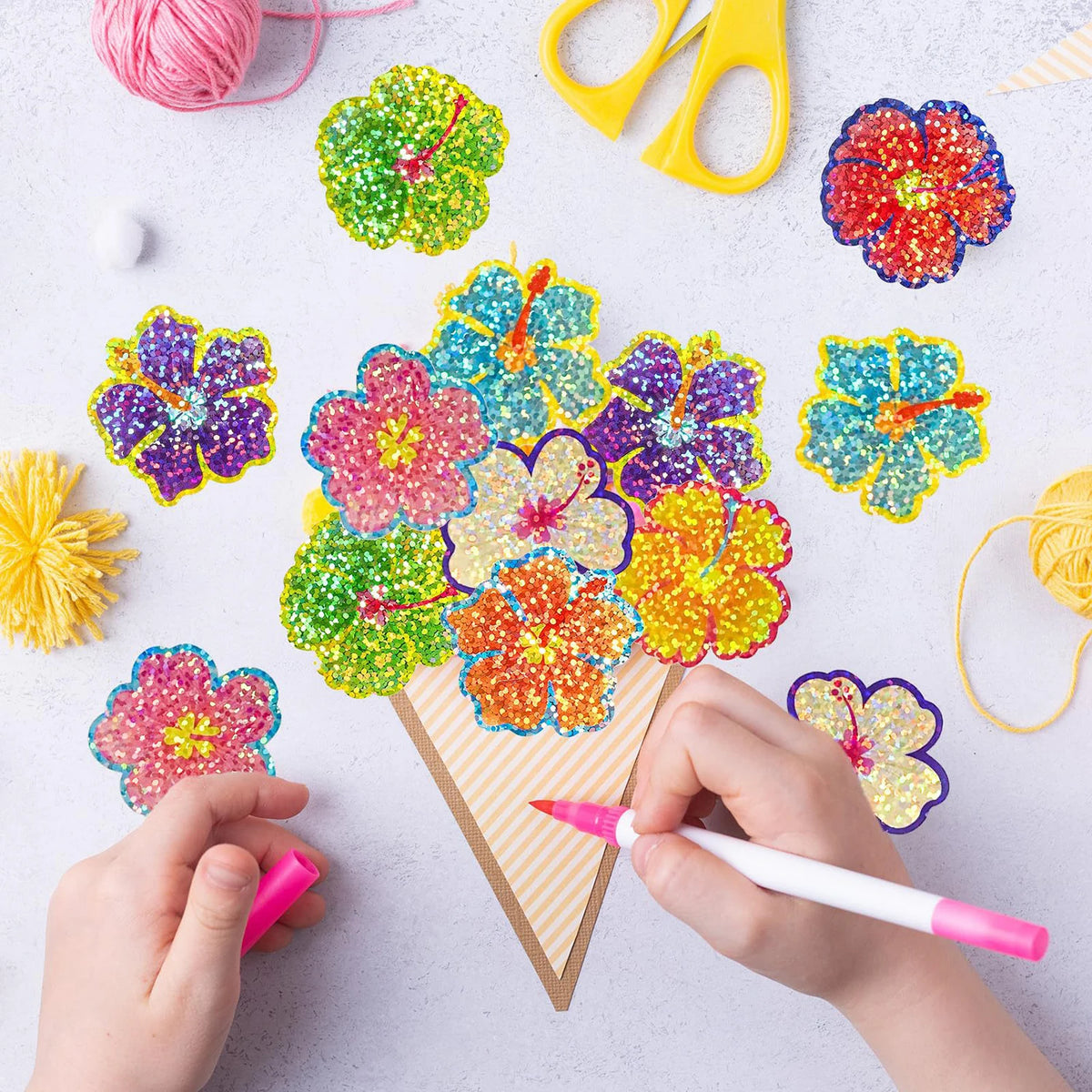 Hands are applying glitter flower round stickers onto a cardboard shape for crafts or party favors.