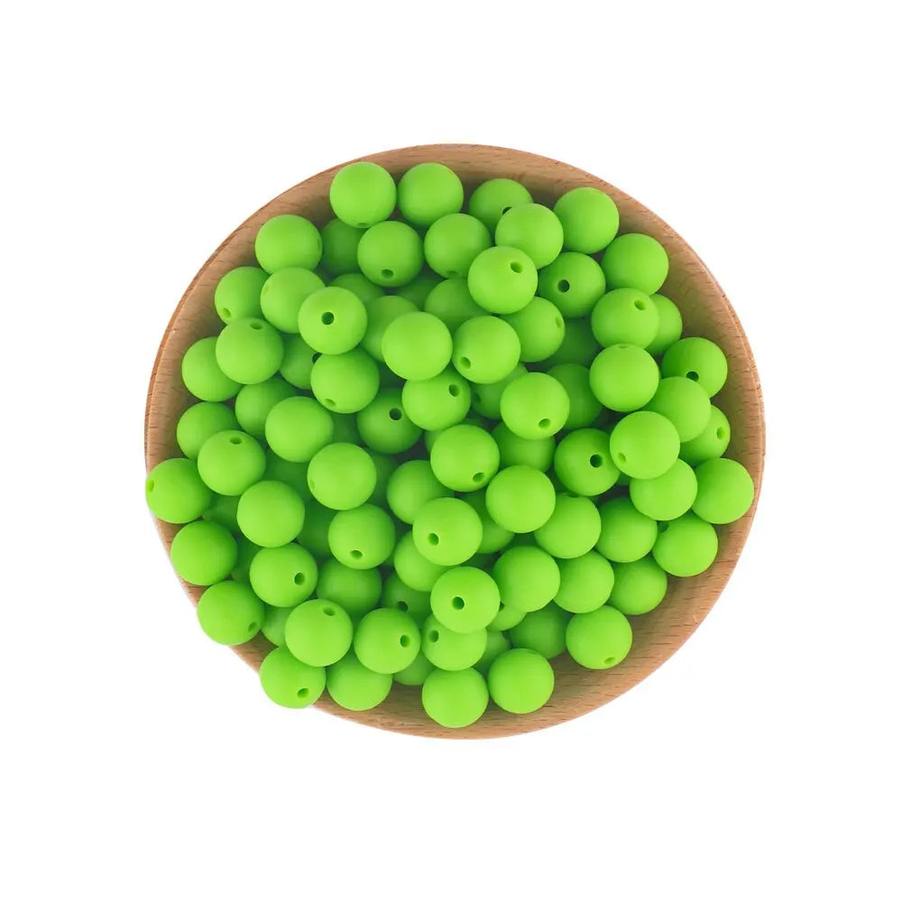 A wooden bowl filled with bright green silicone round beads for jewelry making and DIY crafts