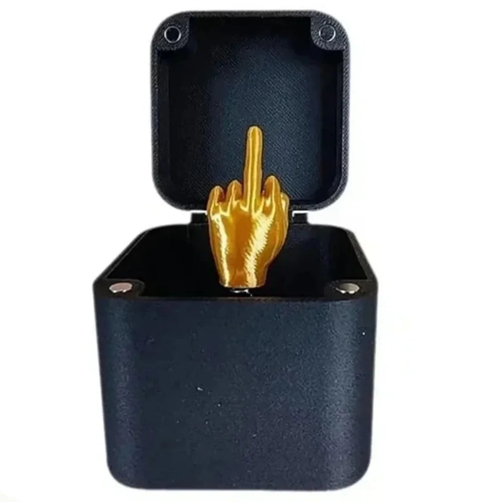 A black pop-up gift box with a gold middle finger hand visible inside.