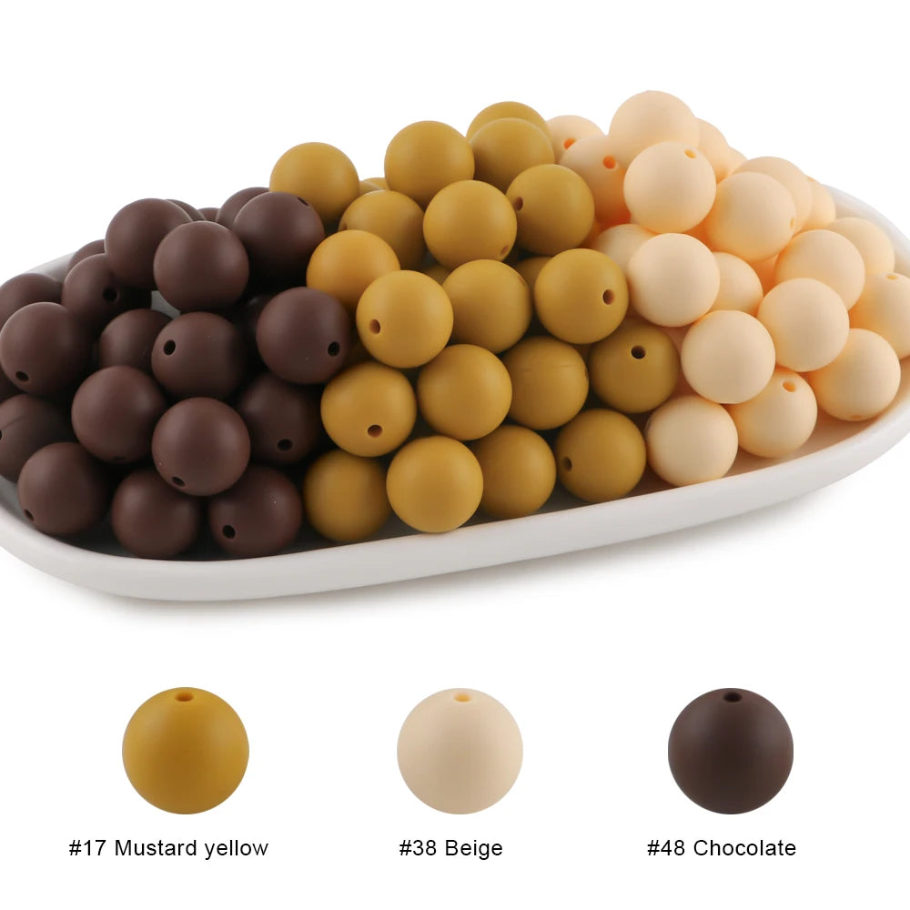 A collection of round silicone beads in various shades including mustard yellow, beige, and chocolate.