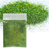 A small plastic bag filled with holographic green glitter powder next to a pile of loose green glitter.