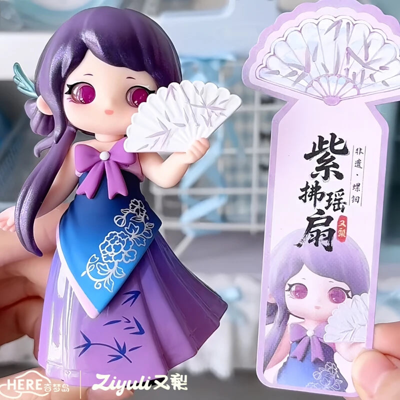A figurine of a girl with purple hair wearing a purple dress and holding a white flower, next to its packaging.