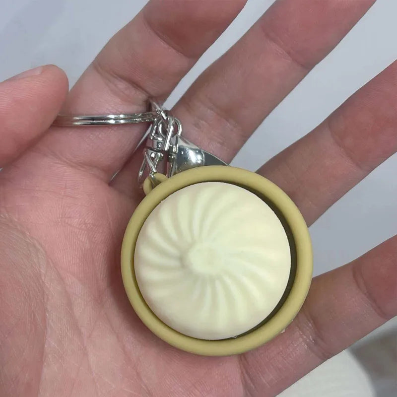 A white silicone fidget toy with a ribbed texture is attached to a silver keychain.