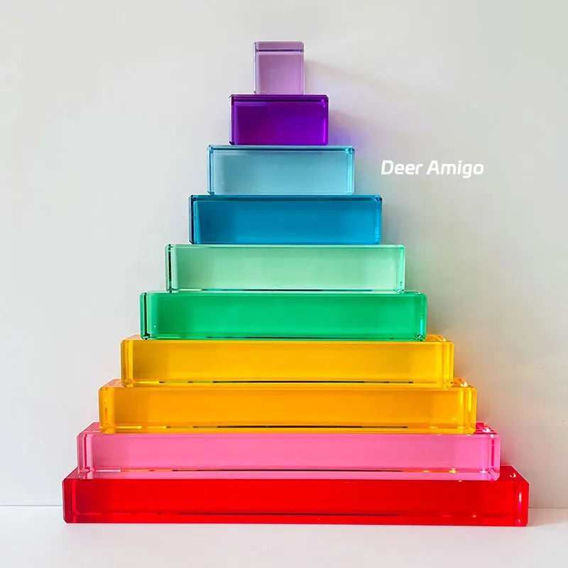 A tower of rainbow acrylic building blocks in various shades of purple, blue, green, yellow, and pink.