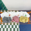 A set of white t-shirts and yellow plaid shorts laid out on a wire basket.