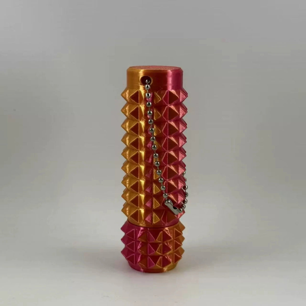 A vibrant orange and pink spike roller fidget toy with a silver keychain attached.