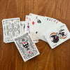 A stack of black and white poker cards is displayed on a wooden surface.