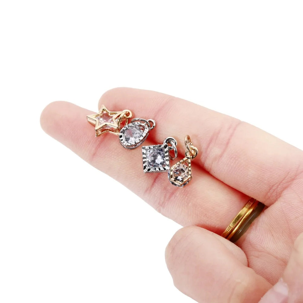 Gold and silver rhinestone heart charms for jewelry making displayed on a hand.