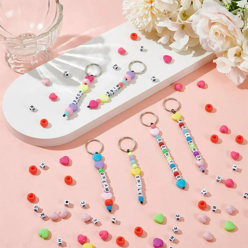 A white tray holds various colorful beads and a DIY beaded keychain making kit with jump rings.