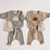 A set of cozy cotton baby girl clothing featuring a long-sleeve top and matching pants in gray and beige tones.