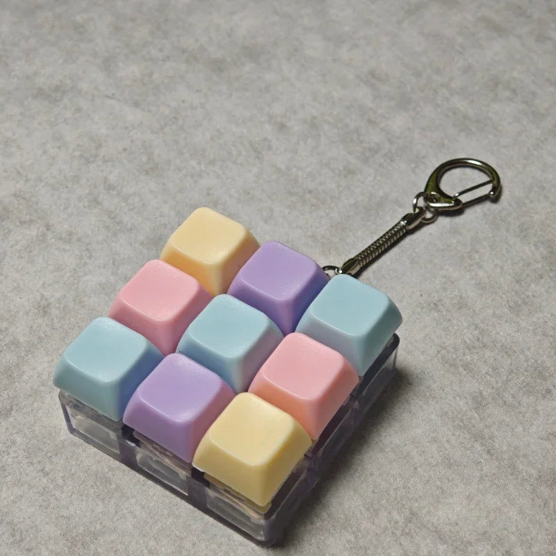 A clear plastic container filled with colorful fidget cubes and a silver keychain.