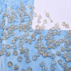A collection of clear and yellowish glass beads shaped like lily of the valley flowers scattered on a white background.