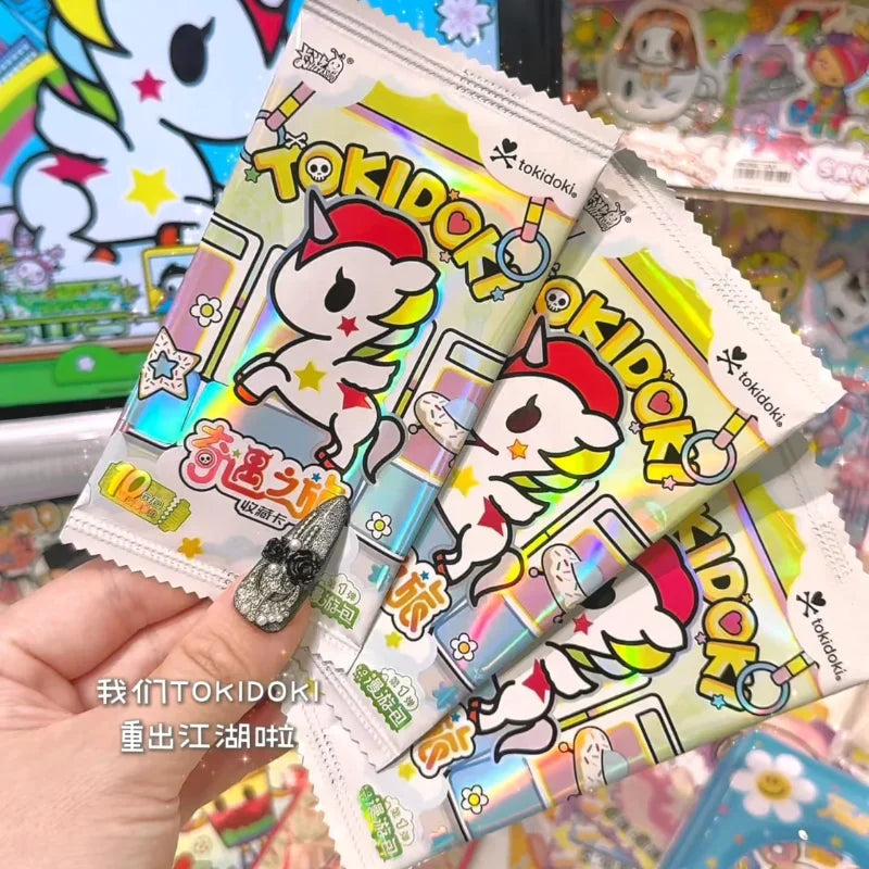 A hand holds several packs of Tokidoki collectible cards featuring a unicorn design.
