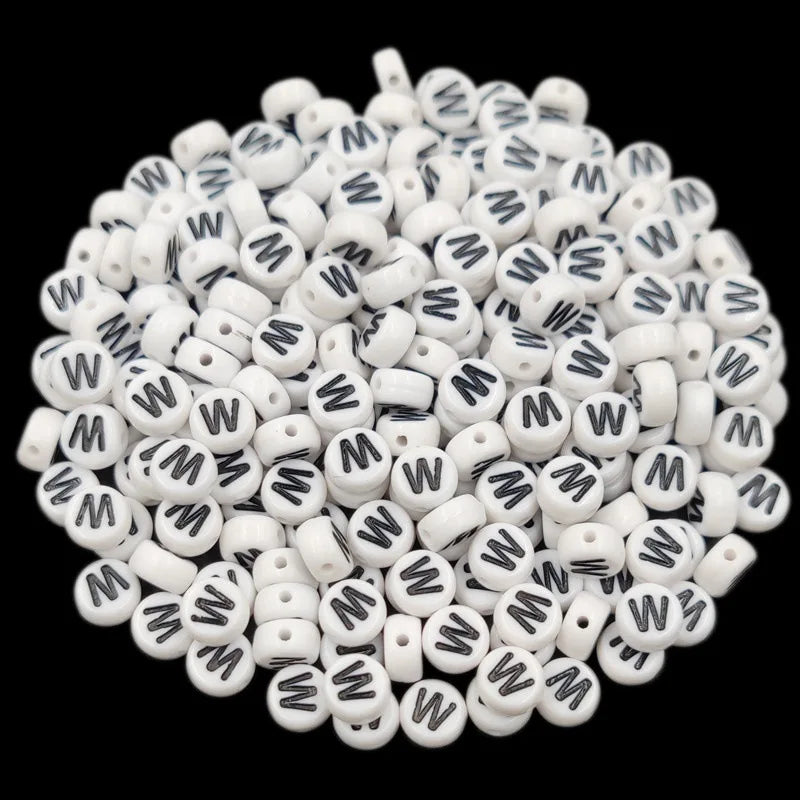 A pile of small white acrylic alphabet letter beads for jewelry making