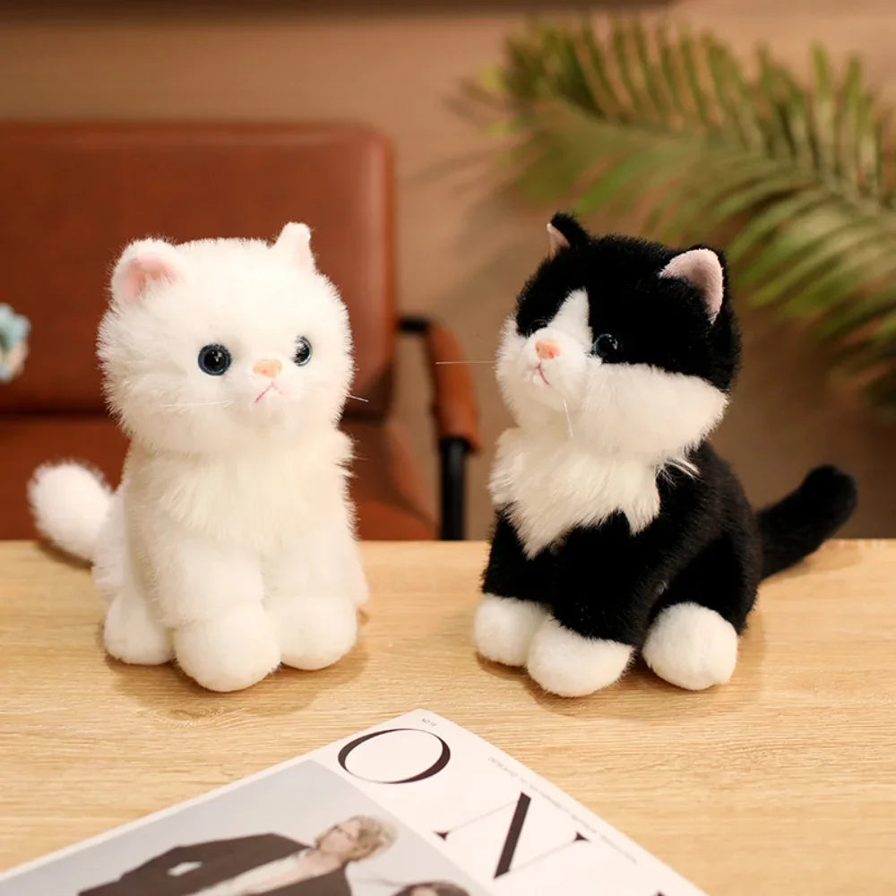 A white and black kitten plush toy sitting on a wooden surface.