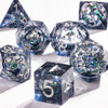 A collection of polyhedral dice with a galaxy finish scattered on a white surface.