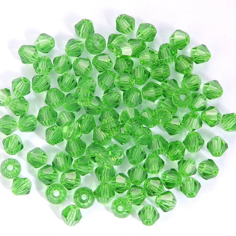 A pile of bright green faceted crystal bicone glass beads for jewelry making.