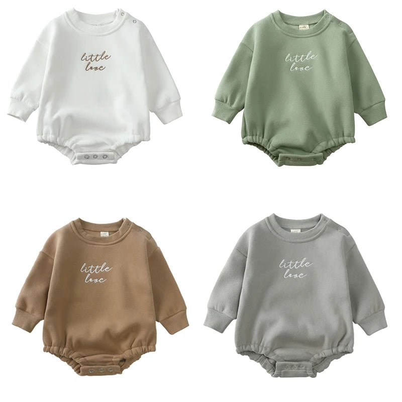 A collection of three embroidered cotton baby rompers in white, sage green, and beige.