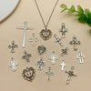 A collection of vintage silver cross charms and pendants scattered on a light beige surface.