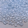 Clear, teardrop-shaped water drop glass beads scattered on a white surface for jewelry making