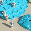 A set of white and blue astronaut figures are placed on a blue, wavy plastic tree balance game board.