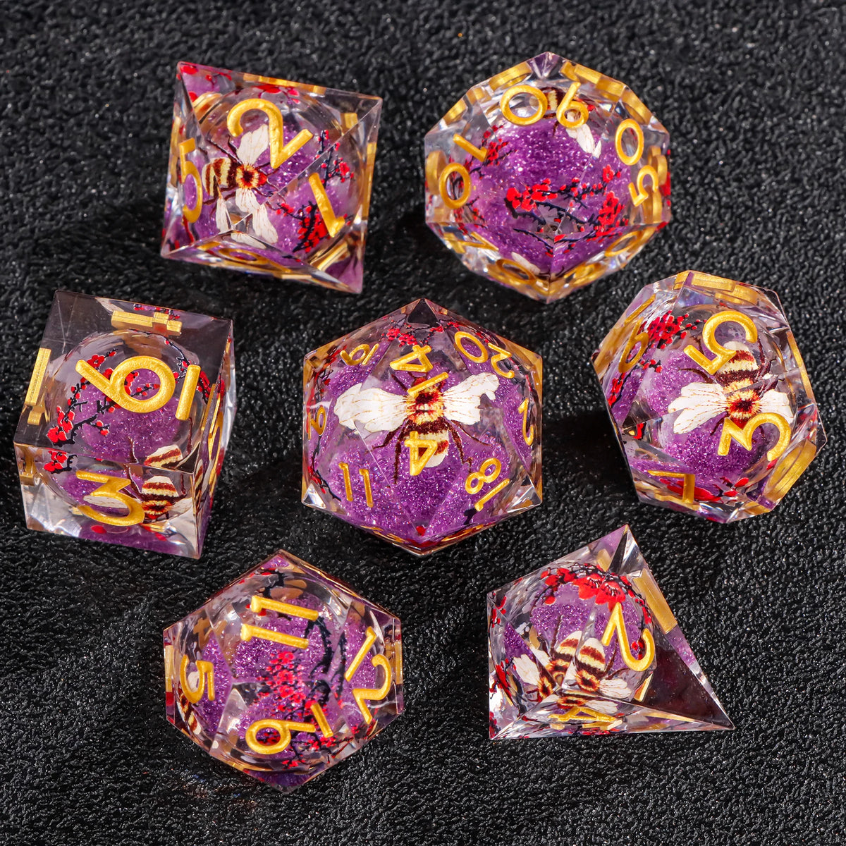 A collection of liquid core polyhedral dice in various colors and shapes resting on a dark surface.