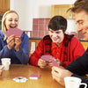 A man and a woman are playing cards around a table, with several decks scattered on the wooden surface.
