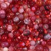 A close-up view of a vibrant mix of red, pink, and amber glass beads for DIY jewelry making