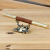 Brass crab figurine with a wooden handle resting on a light wood surface.