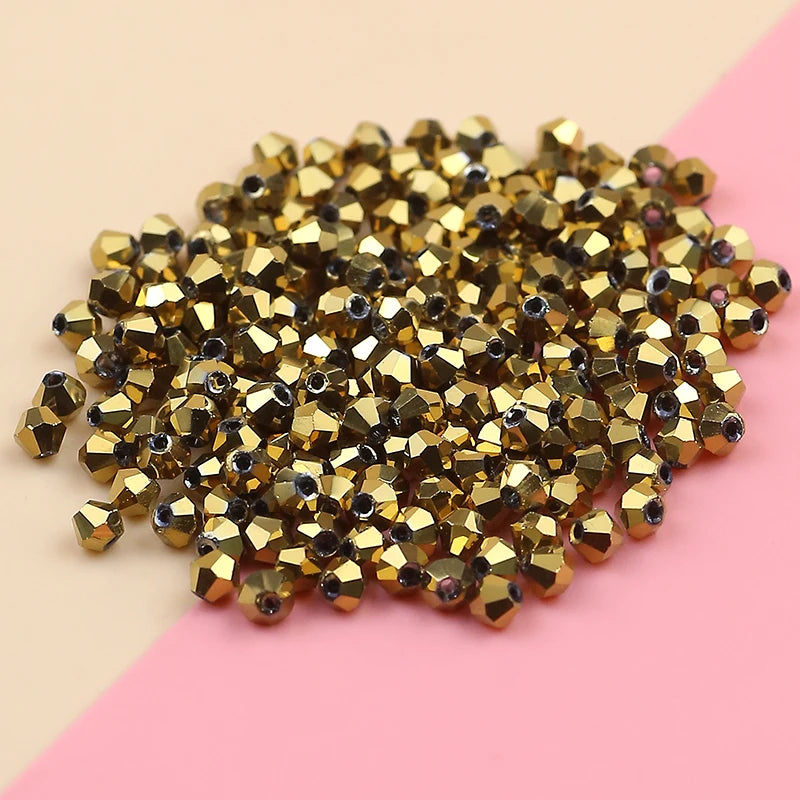A pile of small, gold-colored electroplated crystal glass beads for jewelry making.