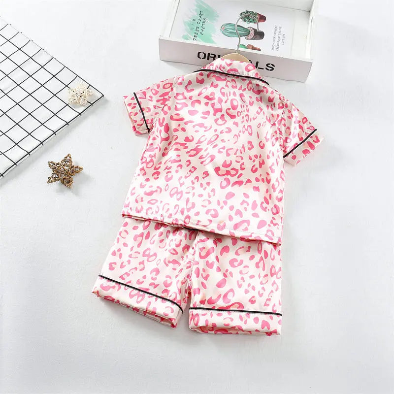 A pink leopard print toddler pajama set with black trim displayed on a white background.