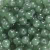 A close-up view of small, round, translucent green glass beads for DIY jewelry making.