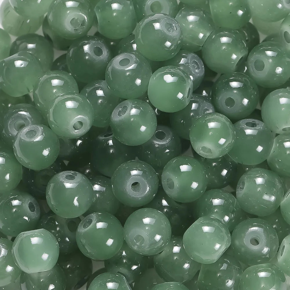 A close-up view of small, round, translucent green glass beads for DIY jewelry making.