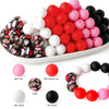 A collection of soft food-grade silicone beads in various colors including pink red and black arranged in a row.