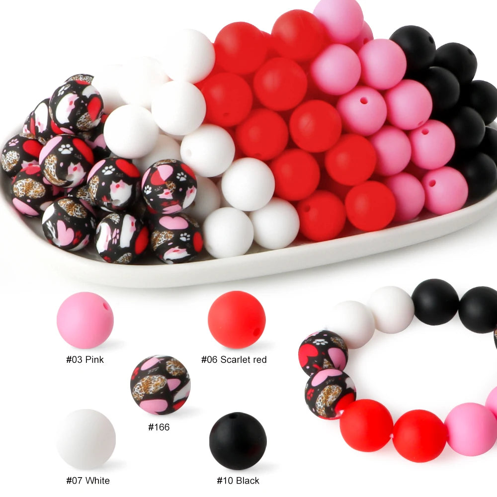 A collection of soft food-grade silicone beads in various colors including pink red and black arranged in a row.