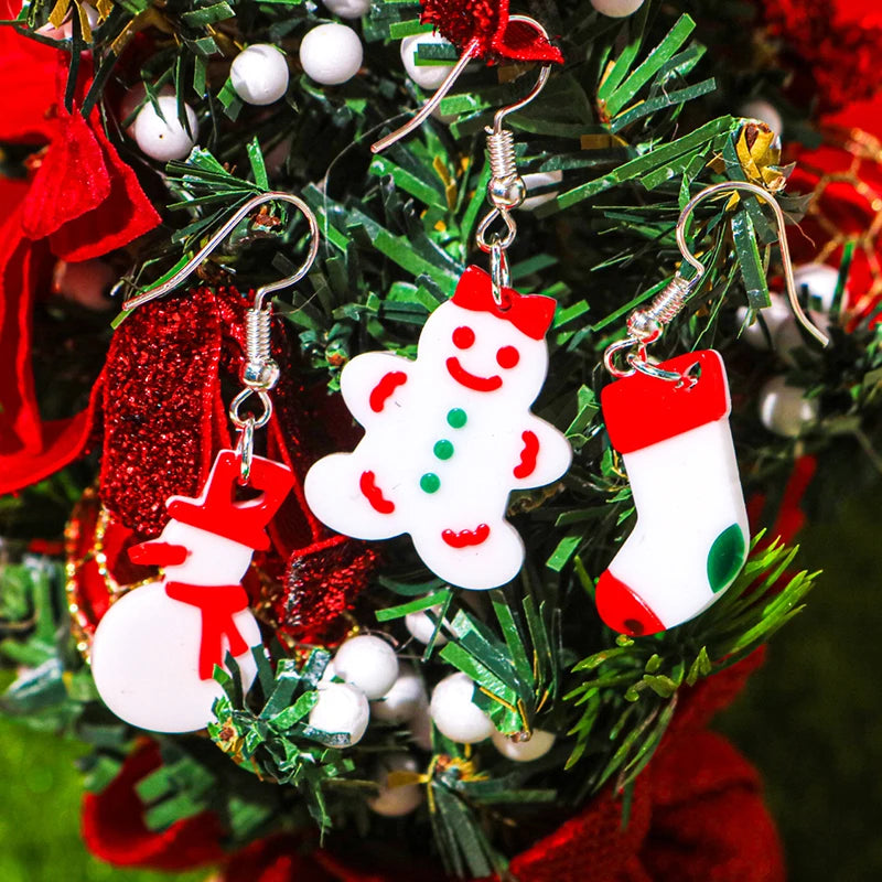 A close-up of festive Christmas silicone molds shaped like snowmen and stockings hanging on a green pine branch.