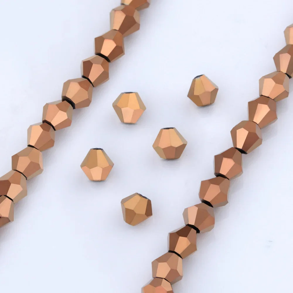 A collection of small, faceted glass beads in a warm copper or rose gold color arranged in linear strands.