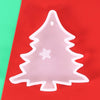 A clear silicone mold shaped like a Christmas tree with a star cutout, resting on a red surface.