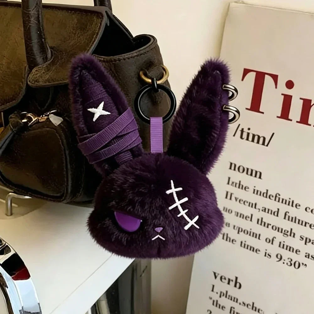 A dark purple gothic bunny plush keychain featuring a bandage design and a gold-colored loop.