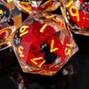 A close-up of a translucent red resin die with gold numbers and a black silhouette of a cat, reflecting on a dark surface.