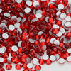 A close-up view of red and clear glass crystal flatback rhinestones scattered on a white surface.
