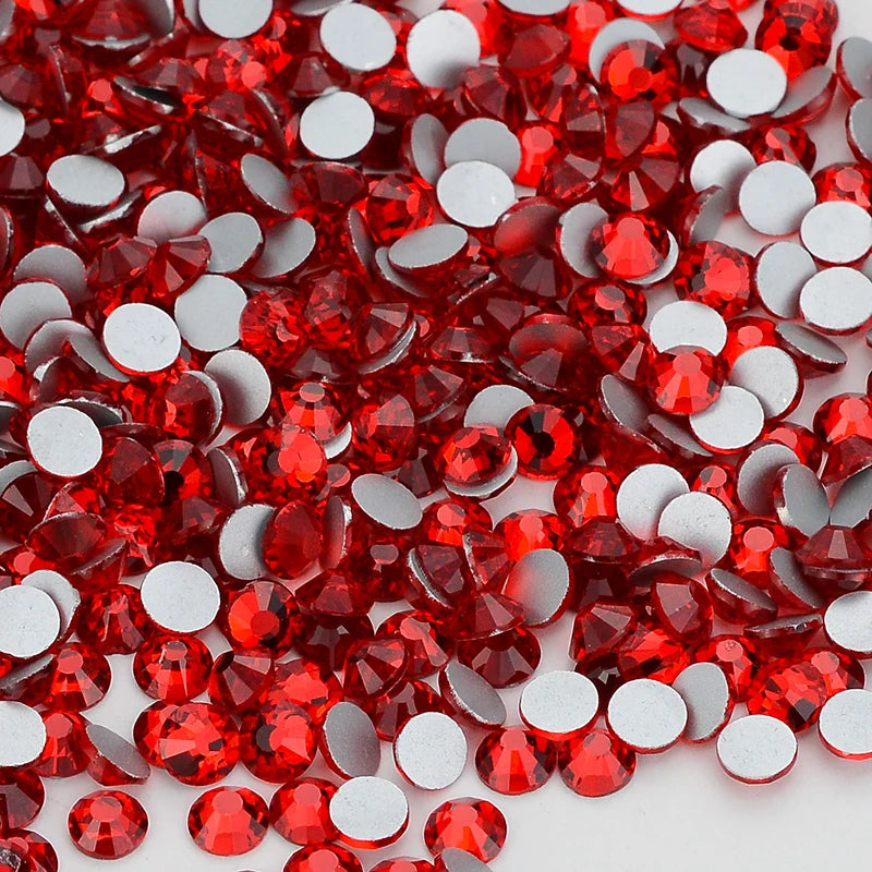 A close-up view of red and clear glass crystal flatback rhinestones scattered on a white surface.