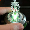 A hand holds a Ben 10 Omnitrix Projector Watch toy, showing a bright green light from the device.