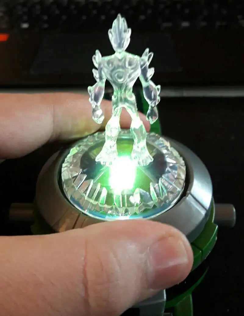 A hand holds a Ben 10 Omnitrix Projector Watch toy, showing a bright green light from the device.