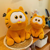 Two orange Garfield plush dolls sitting on a wooden surface.