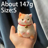 A small, orange and white cat-shaped squishy stress relief toy is held in a person's hand.