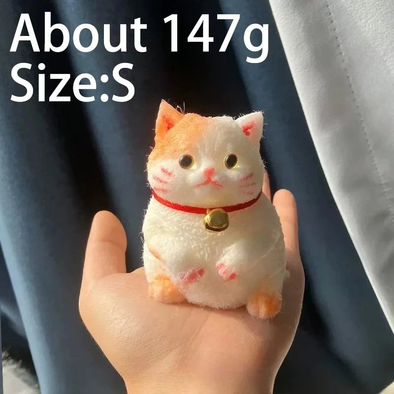 A small, orange and white cat-shaped squishy stress relief toy is held in a person's hand.