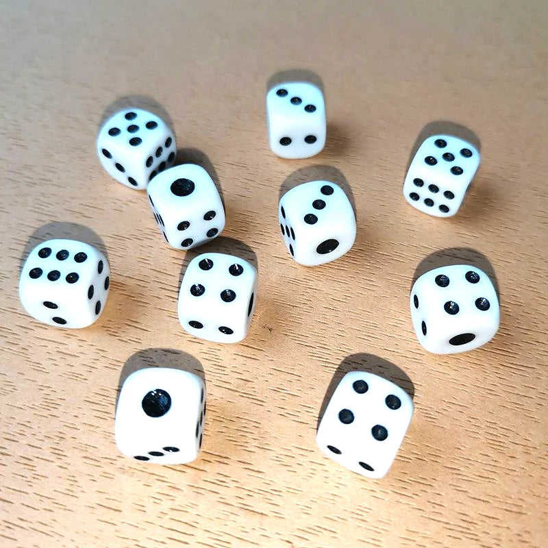 A collection of ten white and black six-sided dice scattered on a light wooden surface.