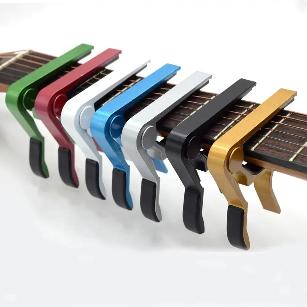 A row of colorful aluminum alloy quick-change guitar capos with black and silver tuning pegs.