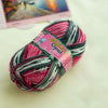 A ball of pink and gray Opal 4-ply sock yarn with a label showing the weight and ply count.